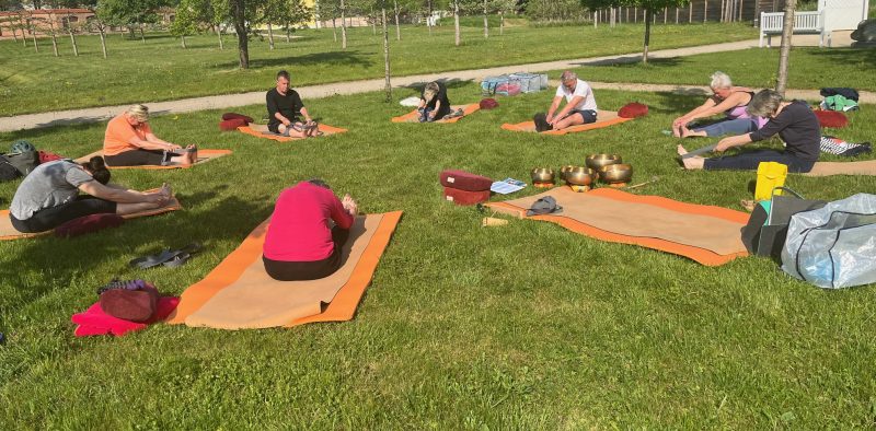Teilnehmende bei einer Klangyogastunde im Klostergarten, im Kreis praktizierend auf Yogamatten