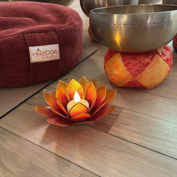 Klangschalen, Meditationskissen und eine brennende Kerze in einem ruhigen Innenraum für eine Klangyogastunde