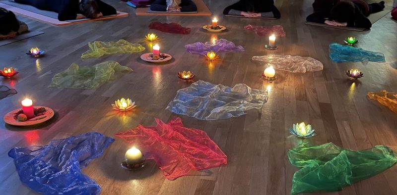 Gruppe von Menschen bei einer besinnlichen Yogastunde zum Jahresabschluss im Kerzenschein